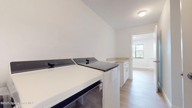 laundry room with light wood-style floors, cabinet space, baseboards, and separate washer and dryer