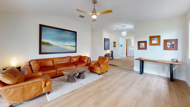 living room featuring visible vents, light wood-style floors, a ceiling fan, vaulted ceiling, and baseboards