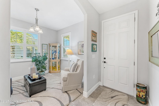 entryway featuring baseboards, arched walkways, and a chandelier