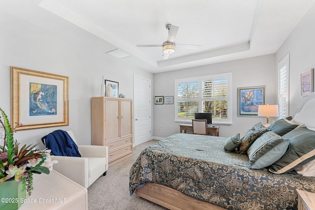 bedroom with light carpet, a textured ceiling, a raised ceiling, and baseboards