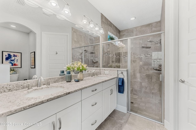 bathroom featuring a shower stall, double vanity, and a sink