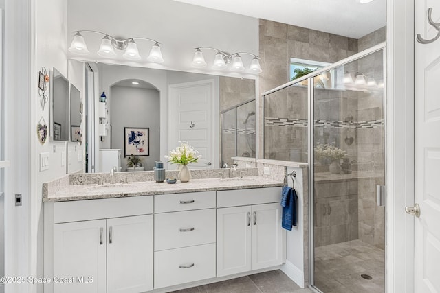 bathroom with double vanity, a shower stall, and a sink