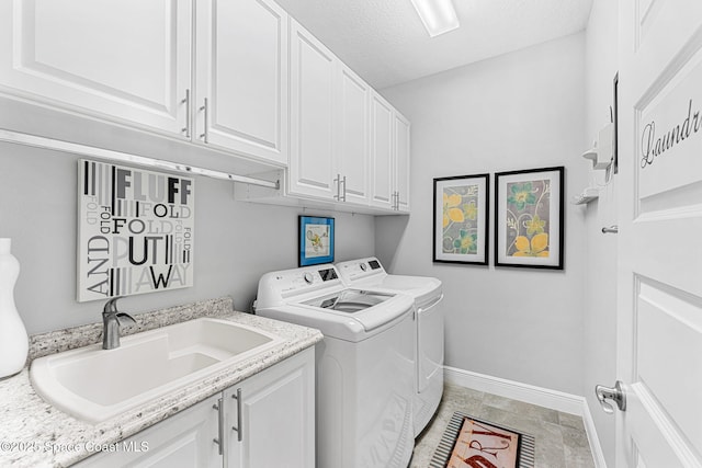 washroom featuring independent washer and dryer, a sink, a textured ceiling, cabinet space, and baseboards