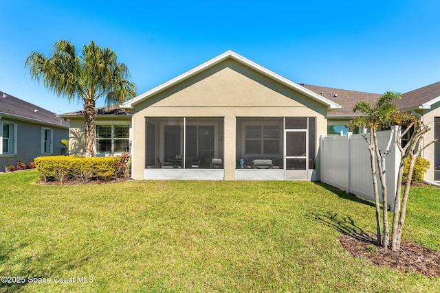 back of property with stucco siding, a lawn, a sunroom, and fence