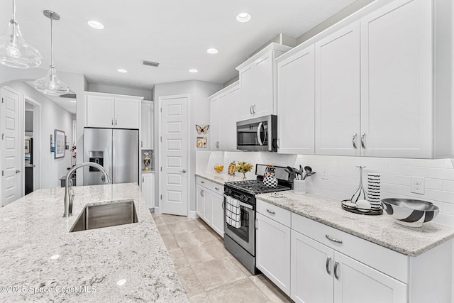 kitchen with decorative backsplash, white cabinetry, appliances with stainless steel finishes, and a sink