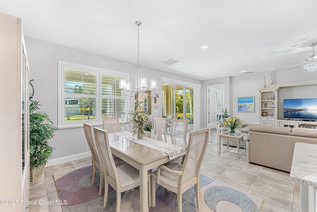 dining area with plenty of natural light, ceiling fan with notable chandelier, visible vents, and baseboards