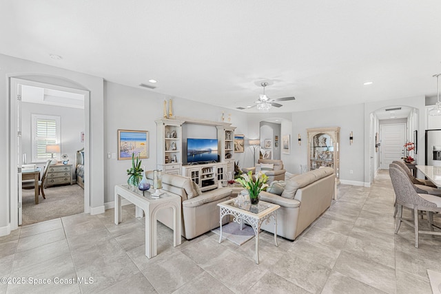 living room with visible vents, arched walkways, baseboards, and ceiling fan