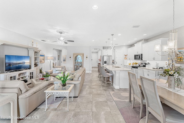 living area featuring recessed lighting, visible vents, arched walkways, and ceiling fan with notable chandelier