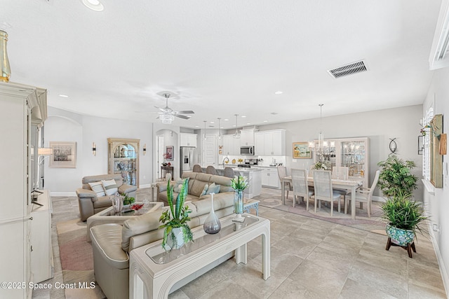 living area with visible vents, baseboards, recessed lighting, ceiling fan with notable chandelier, and arched walkways