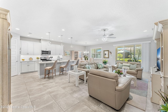 living room featuring light tile patterned floors, recessed lighting, ceiling fan with notable chandelier, and a textured ceiling