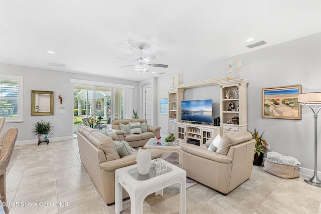 living area featuring light tile patterned floors, visible vents, baseboards, and a ceiling fan