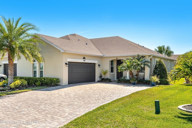 view of front of house with stucco siding, decorative driveway, a garage, and a front yard