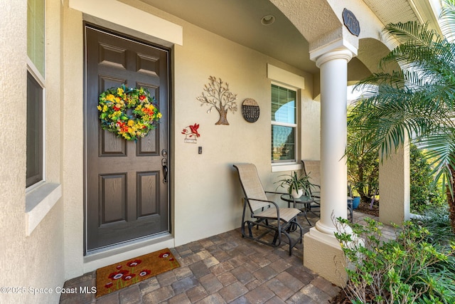 property entrance with a porch and stucco siding