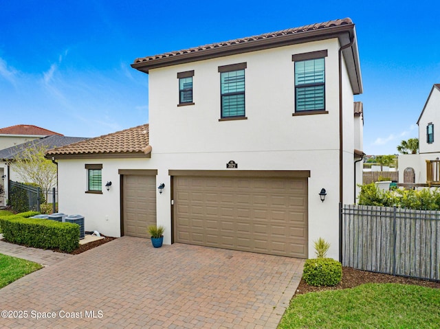 mediterranean / spanish-style home featuring a tiled roof, stucco siding, and fence