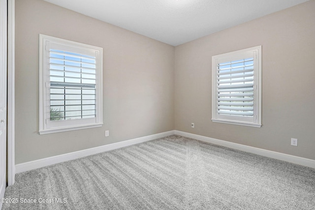 spare room with baseboards and carpet floors