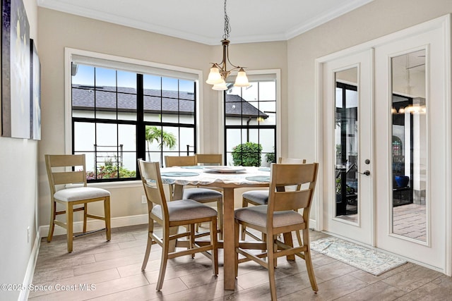 dining space with baseboards, wood finish floors, ornamental molding, french doors, and a notable chandelier