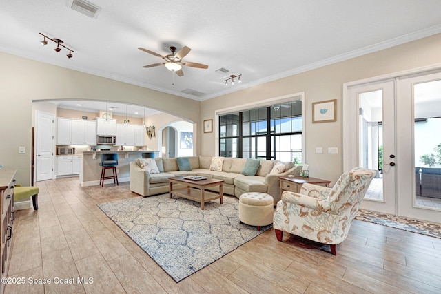 living area with visible vents, arched walkways, ornamental molding, and french doors