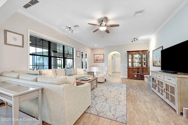 living area with ceiling fan, visible vents, arched walkways, and ornamental molding