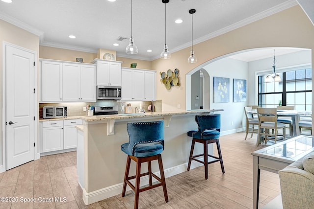 kitchen with stainless steel appliances, arched walkways, tasteful backsplash, and a breakfast bar