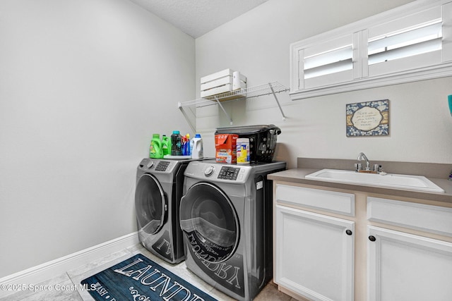 washroom featuring baseboards, washer and clothes dryer, light tile patterned floors, cabinet space, and a sink