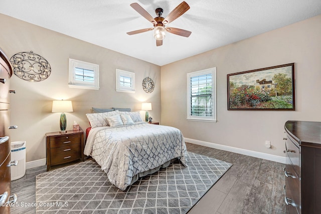 bedroom featuring multiple windows, wood finished floors, and baseboards