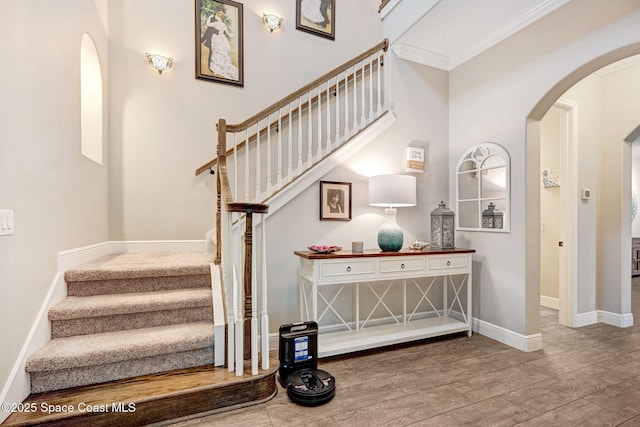 stairs featuring baseboards, arched walkways, and ornamental molding