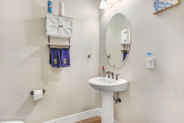 bathroom featuring wood finished floors, baseboards, and a sink