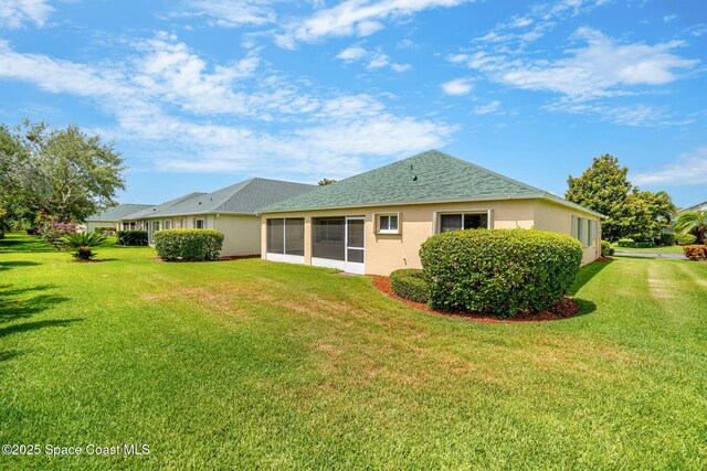 rear view of property with stucco siding, a lawn, and a shingled roof