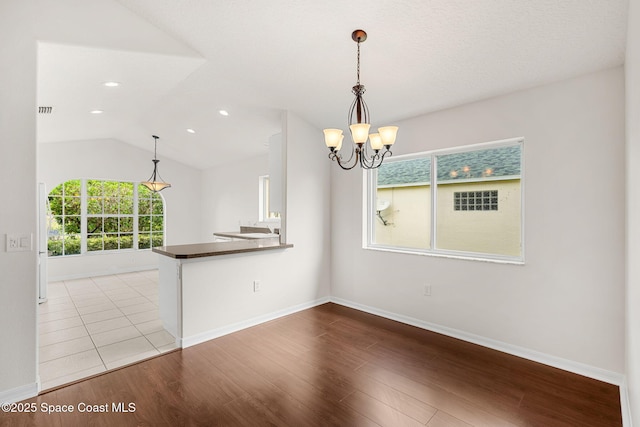 spare room with wood finished floors, a chandelier, vaulted ceiling, baseboards, and recessed lighting