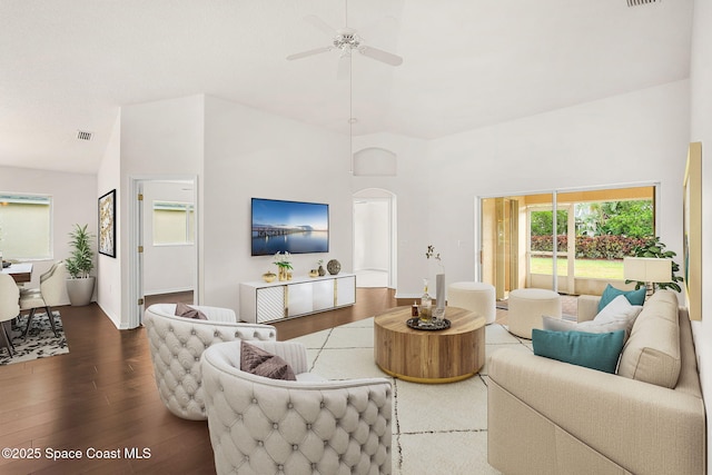 living room featuring wood finished floors, ceiling fan, high vaulted ceiling, arched walkways, and baseboards