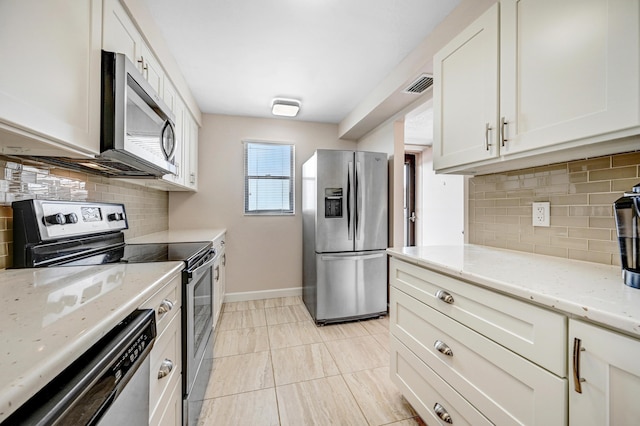 kitchen featuring appliances with stainless steel finishes, light stone countertops, visible vents, and tasteful backsplash