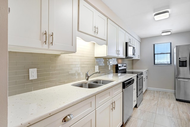 kitchen with decorative backsplash, light stone counters, appliances with stainless steel finishes, white cabinetry, and a sink