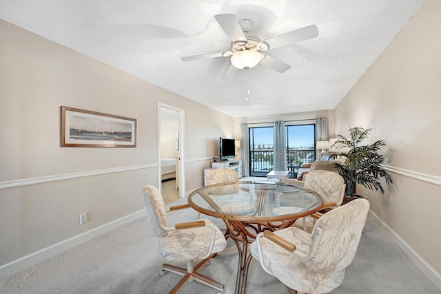 dining space with a textured ceiling, carpet, a ceiling fan, and baseboards