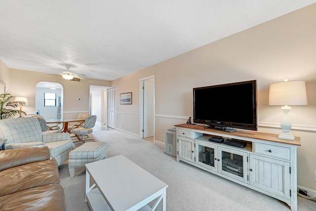 living area featuring light carpet, arched walkways, and a ceiling fan