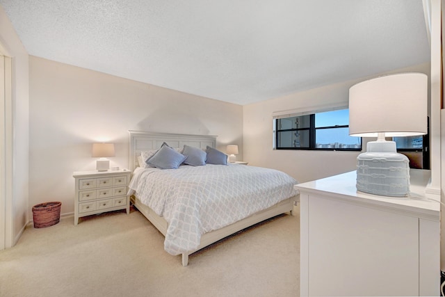 bedroom with light carpet, a textured ceiling, and baseboards