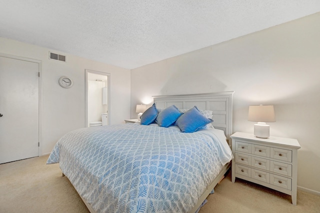 bedroom with light colored carpet, connected bathroom, visible vents, and a textured ceiling