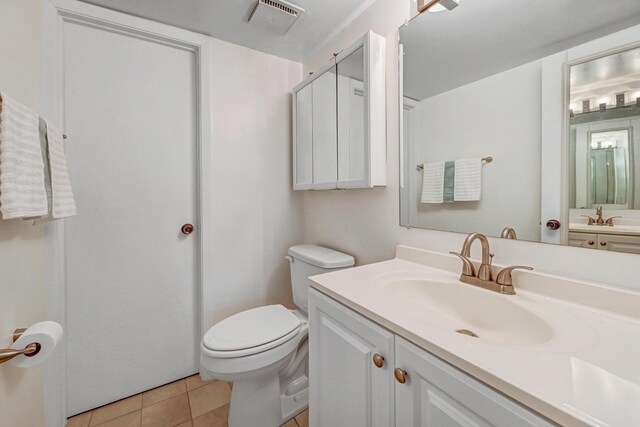 bathroom with toilet, tile patterned flooring, visible vents, and vanity