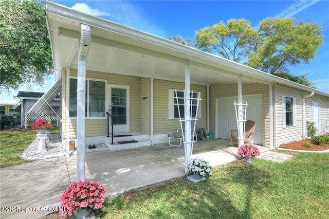 rear view of property with a garage, concrete driveway, and a lawn