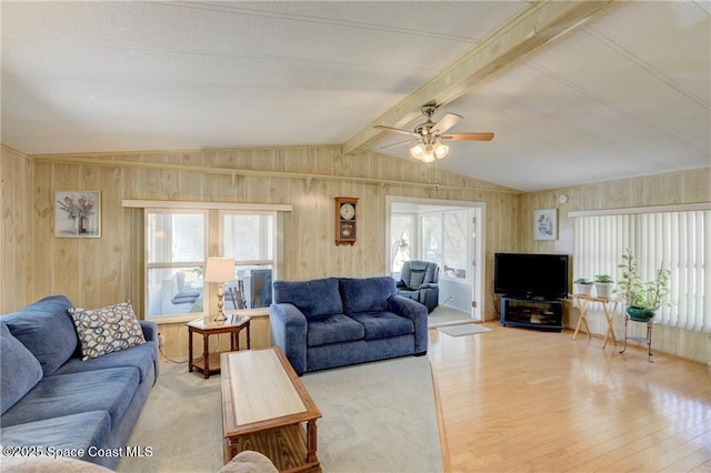 living area with vaulted ceiling with beams, wood walls, a ceiling fan, and wood finished floors