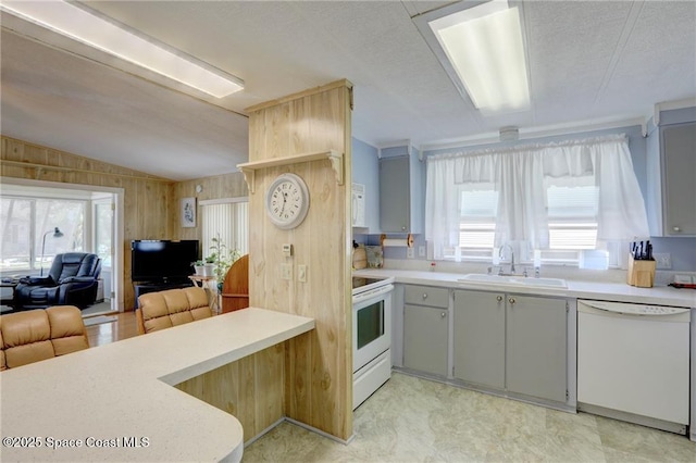 kitchen featuring white appliances, lofted ceiling, open floor plan, light countertops, and a sink