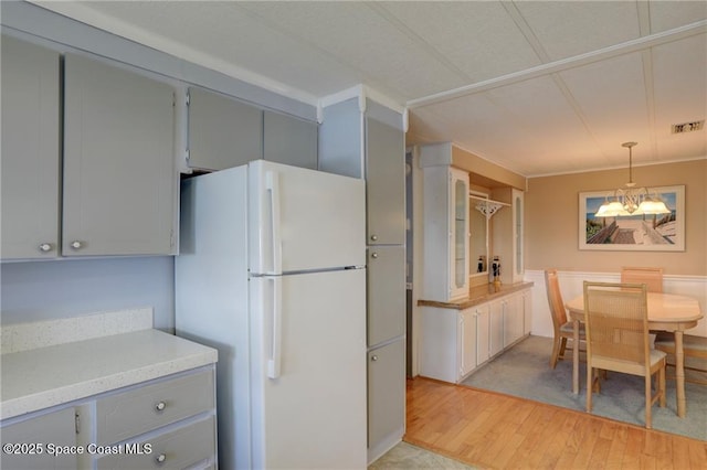 kitchen with visible vents, light wood-style floors, light countertops, gray cabinets, and freestanding refrigerator