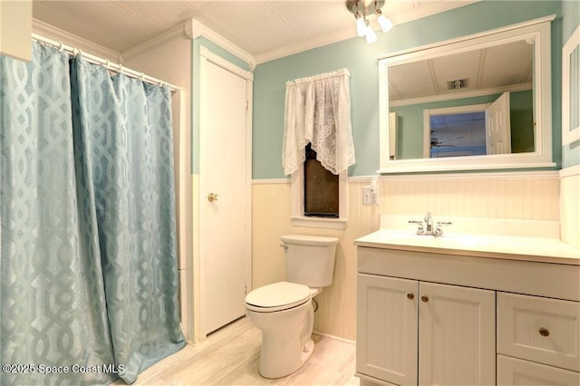 full bath with toilet, a wainscoted wall, wood finished floors, vanity, and crown molding