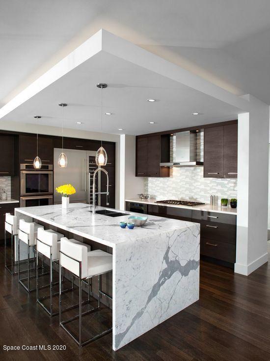 kitchen featuring a sink, a breakfast bar area, dark brown cabinets, and wall chimney exhaust hood