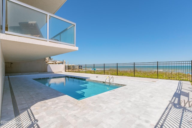 view of swimming pool with a fenced in pool, a beach view, a water view, fence, and a patio area