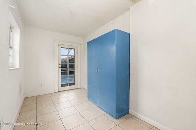 spare room featuring light tile patterned floors and baseboards