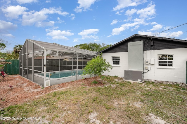 back of property featuring glass enclosure, cooling unit, a fenced in pool, and fence