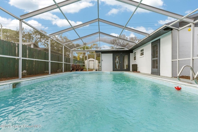 view of swimming pool featuring a fenced in pool, an outbuilding, a lanai, fence, and a shed