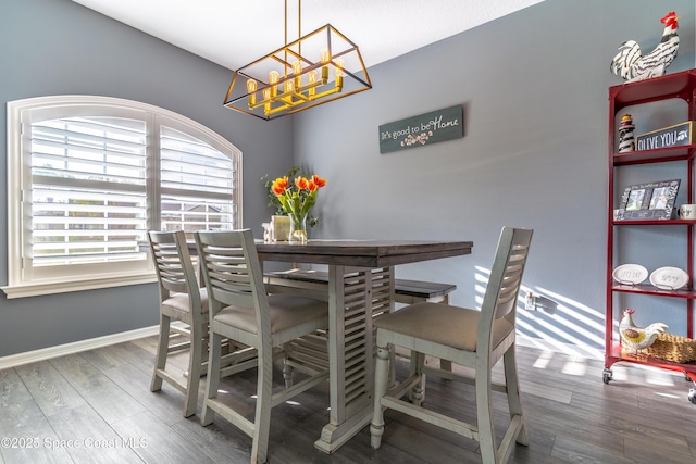 dining space with baseboards, a chandelier, and wood finished floors