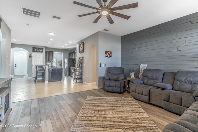 living area featuring wood walls, an accent wall, visible vents, and arched walkways