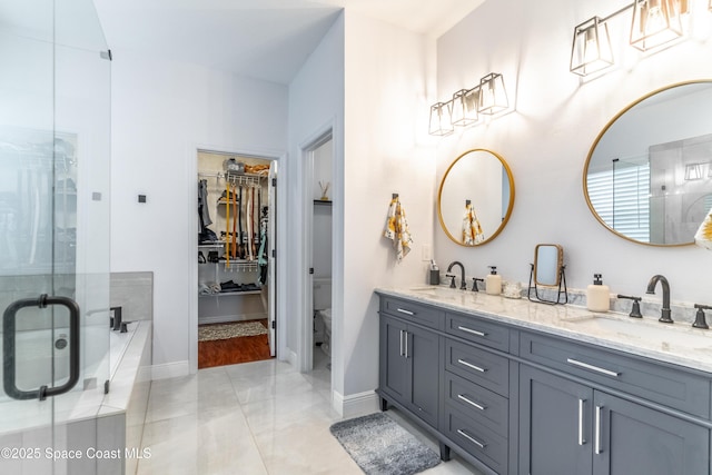 full bathroom with double vanity, a shower stall, toilet, and a sink